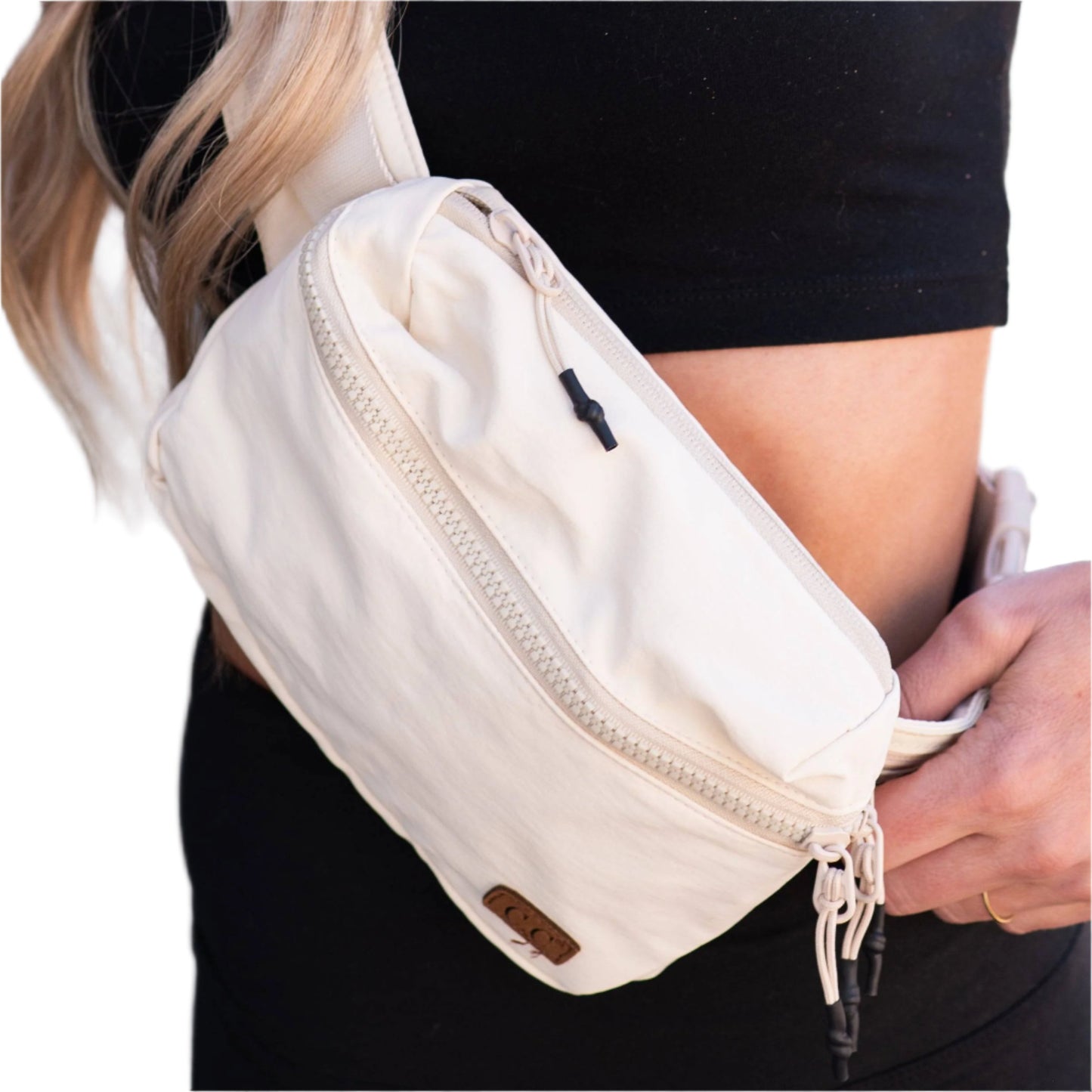 Beige CC Brand crossbody bag worn with black athleisure outfit